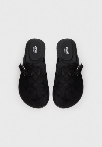 Black quilted slip-on clogs with adjustable buckle straps and Moschino Milano branded cushioned insoles.