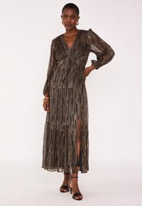 Robe maxi en tissu métallique avec un décolleté en V, de longues manches bouffantes, un design à volants et une fente sur le côté. La couleur est noire avec des accents argentés.