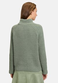 Hellgrüner Strickpullover mit hohem Kragen und gerippten Bündchen. Texturiertes Muster und lässige Passform, mit geradem Saum.