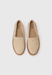 Beige suédist slip-on kingad, millel on ümar nina, elastsed külgtaskud ja punutud köie detailid tallal. TOMS logo sisetaldadel.