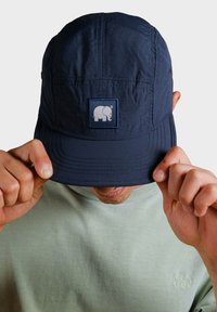 Námořnická čepice s přední nášivkou s bílým slonem. Lehká tkanina, strukturovaný tvar s křivým vrcholem, texturovaný povrch a detaily prošití.