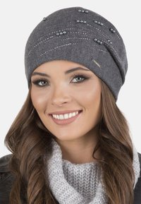 Căciulă tricotată gri cu o suprafață texturată, decorată cu perle mici și accente metalice. Material moale cu un design ajustat și o ușoară cădere.