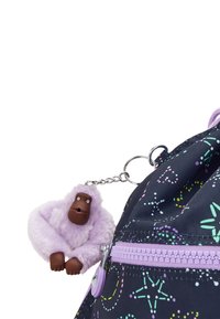 En blød lilla gorilla nøglering hængende fra en sort rygsæk med pastelfarvede stjerner og prikker samt en lilla lynlås.