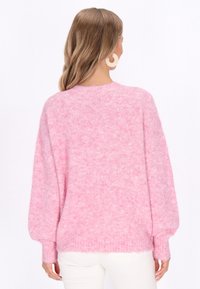 Różowy, oversize sweter wykonany z miękkiego, puszystego materiału, z opadającymi ramionami i prążkowanymi mankietami. Posiada okrągły dekolt i subtelną teksturę.