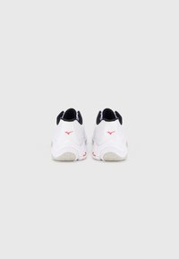 Λευκά αθλητικά παπούτσια με μαύρες λεπτομέρειες. Άνω μέρος από δίχτυ, μαξιλαρωμένη φτέρνα, κόκκινη λεπτομέρεια λογότυπου στο πίσω μέρος, υφή λευκής εξωτερικής σόλας.