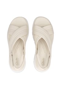 Beige leren sandalen met gekruiste banden, geperforeerde voetbed en witte rubberen zool. Bevat Clarks branding aan de binnenkant.