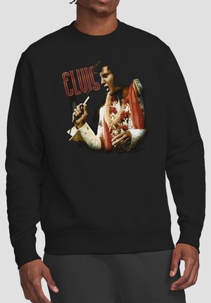 Schwarzer Pullover mit einem bunten Motiv von Elvis Presley, der in ein Mikrofon singt, und dem Schriftzug "Elvis" darüber.