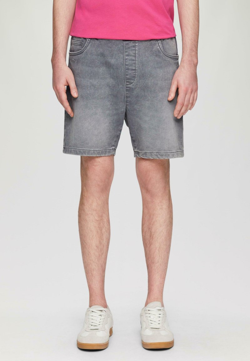 Szare szorty dżinsowe z wypłowiałym wykończeniem, pięcioma kieszeniami i prostym krojem, w połączeniu z białymi sneakersami.