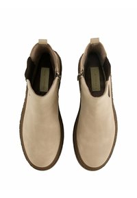 Bottes de chelsea en cuir beige avec une texture lisse, fermeture éclair latérale décorative, intérieur brun contrastant et semelle en caoutchouc. Style classique.