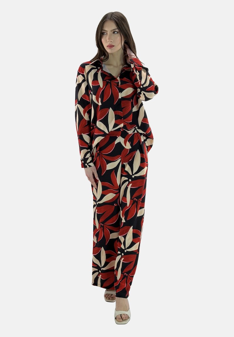 Ensemble composé d'un haut et d'un pantalon à motifs floraux rouges et beiges, avec une coupe décontractée ; tissu texturé ; associé à des sandales à bout ouvert de couleur claire.