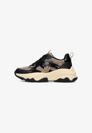 Scarpa sportiva nera e beige con una parte superiore in mesh, dettagli lucidi, suola testurizzata e un design chunky che presenta un pull tab sul tallone.