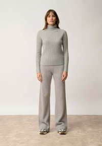 Szary żebrowany sweter z golfem w połączeniu z szerokimi szarymi spodniami o żebrowanym wzorze. Materiał wydaje się miękki, ma gładką teksturę i subtelną elastyczność.