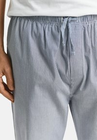 Gestreepte pyjamabroek in lichtblauw en wit. Elastische tailleband met een trekkoord. Zachte stof met een losse pasvorm en verticale strepen.