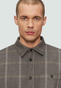 Grijze geruite shirt met een zachte textuur, voorzien van een button-down kraag, zwarte knopen en een borstzak met een knoopdetail.