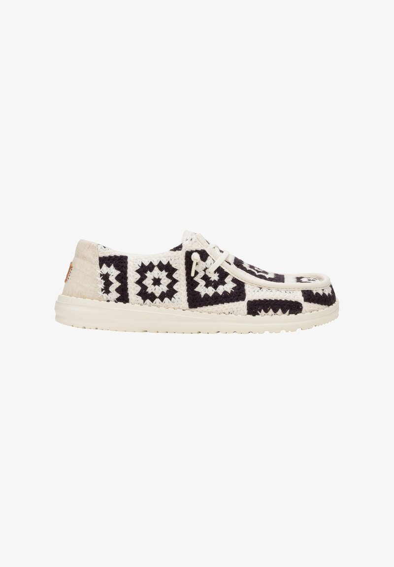 Zwart-wit gestreepte sneaker met een textiel bovenwerk, ronde neus en een lichtgekleurde rubberen zool. Geknoopt ontwerp met minimale accenten.