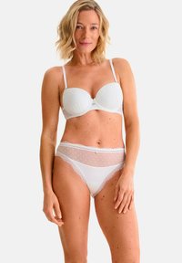 Wit lingerieset met een gepadded beha met een gestructureerd oppervlak en bijpassende doorschijnende slipjes versierd met stippen en kantafwerking.