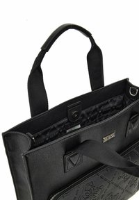 Sac fourre-tout en cuir noir avec motif embossé, anses en tissu, poche intérieure zippée et doublure avec logo. Présente un extérieur lisse et une forme structurée.