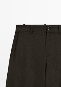 Pantalons en laine marron foncé à coupe ajustée, avec fermeture à bouton, poches avant et une texture subtile.