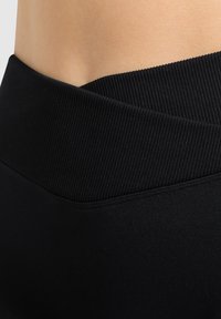 Zwarte high-waisted leggings met een geribde tailleband en een gladde textuur, met een aansluitend ontwerp en zonder zichtbare patronen of accenten.