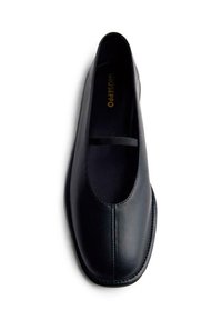 Chaussure slip-on en cuir noir avec un bout arrondi, des coutures minimales et une fine sangle élastique sur le dessus pour un ajustement sûr.