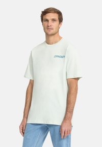 Korte mouwen, lichtgroen T-shirt van katoen met ronde hals, met een blauw "SPYDER" logo op de linkerborst. Gladde textuur.