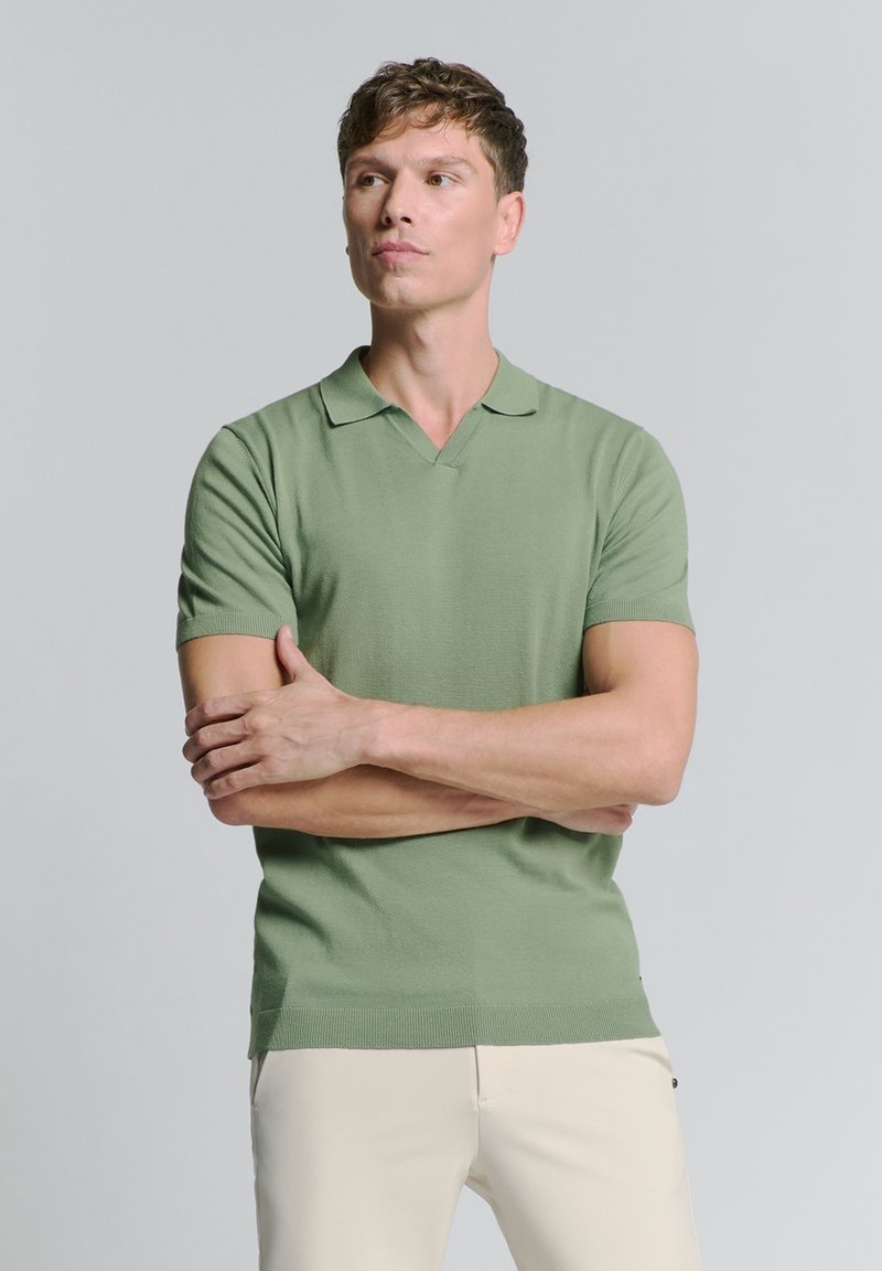 Korte mouwen, V-hals polo shirt in zachtgroene katoenmix. Beschikt over een ribgebreide kraag en manchetten, met een getailleerde pasvorm en een gladde textuur.