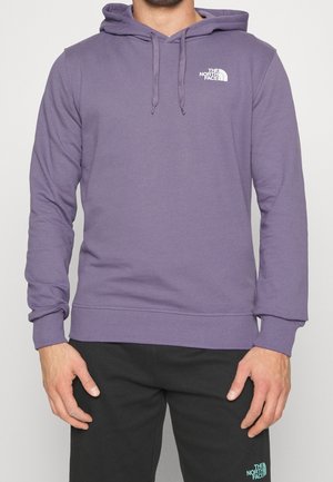 Man draagt een paarse capuchontrui en een zwarte broek, beide met het witte The North Face-logo aan de linkerkant.