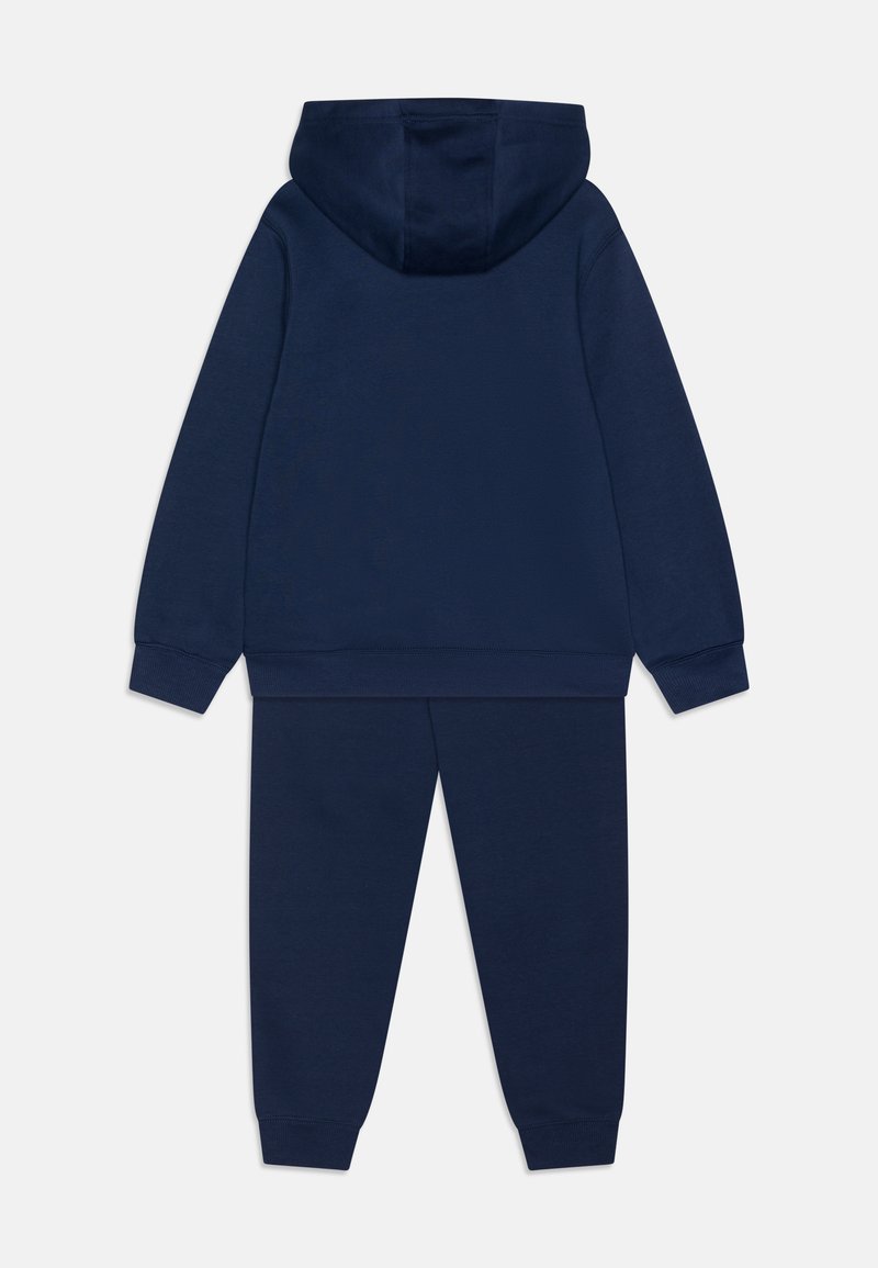 Marineblaue Kapuzenjacke und Jogginghose aus weichem Material. Die Kapuzenjacke hat eine Kapuze und gerippte Bündchen; die Jogginghose hat einen elastischen Bund.