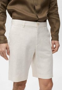 Shorts in lino color beige chiaro con una vestibilità su misura, dotati di chiusura a bottone e tasche laterali per la funzionalità. Tessuto morbido.