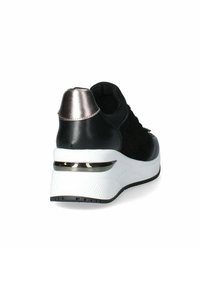 Sneaker nera con retro testurizzato, accento metallico sul tallone e suola bianca chunky con un dettaglio lucido vicino alla base.