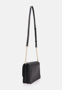 Zwarte faux leren crossbody tas met een gestructureerd ontwerp, gouden kettingriem en verstelbare leren schouderriem. Beschikt over een klep afsluiting.