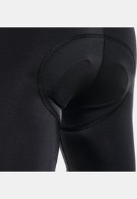 Leggings negros con tela suave y elástica, con un detalle acolchado circular en la parte posterior y costuras de contraste a lo largo de las costuras.