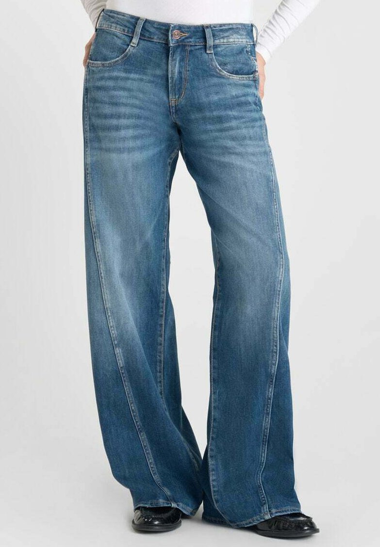 Jean en denim bleu à jambes larges avec une taille haute, présentant un délavage subtil, un design classique à cinq poches et des coutures contrastantes le long des coutures.