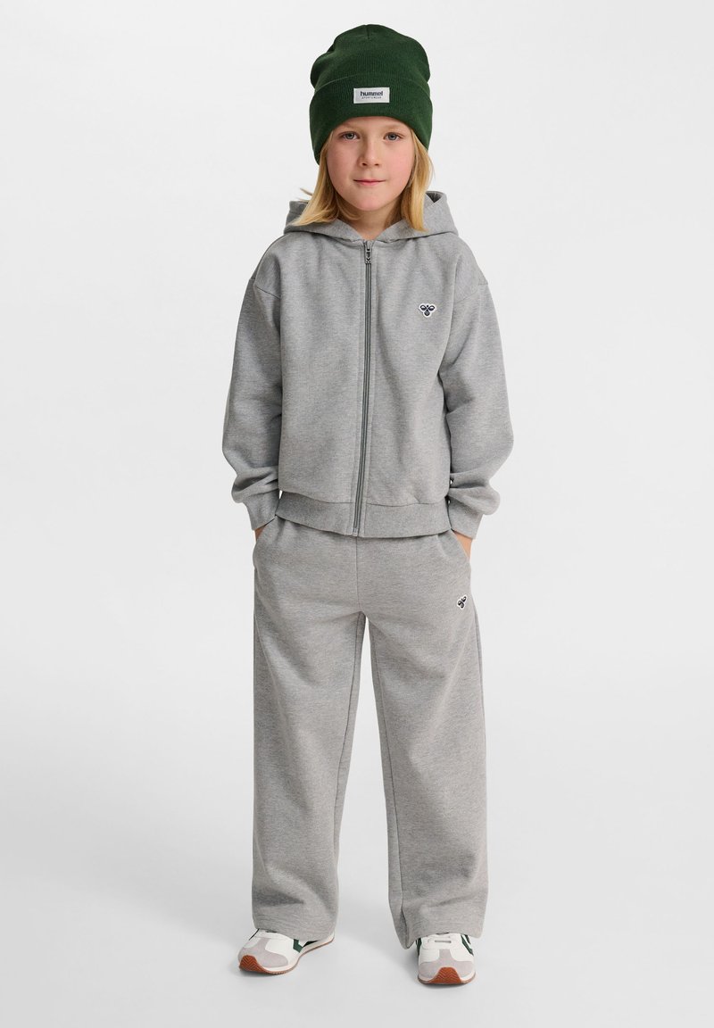 Grå zip-up hoodie och matchande sweatpants i mjukt material, matchat med en grön mössa. Har logotyp på bröstet och byxorna.