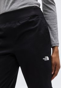 Μαύρο παντελόνι από απαλό ύφασμα με φαρδύ ζωνάρι στη μέση. Διαθέτει λευκό λογότυπο στο μηρό, παρουσιασμένο με γκρι μπλούζα μακρυμάνικη.