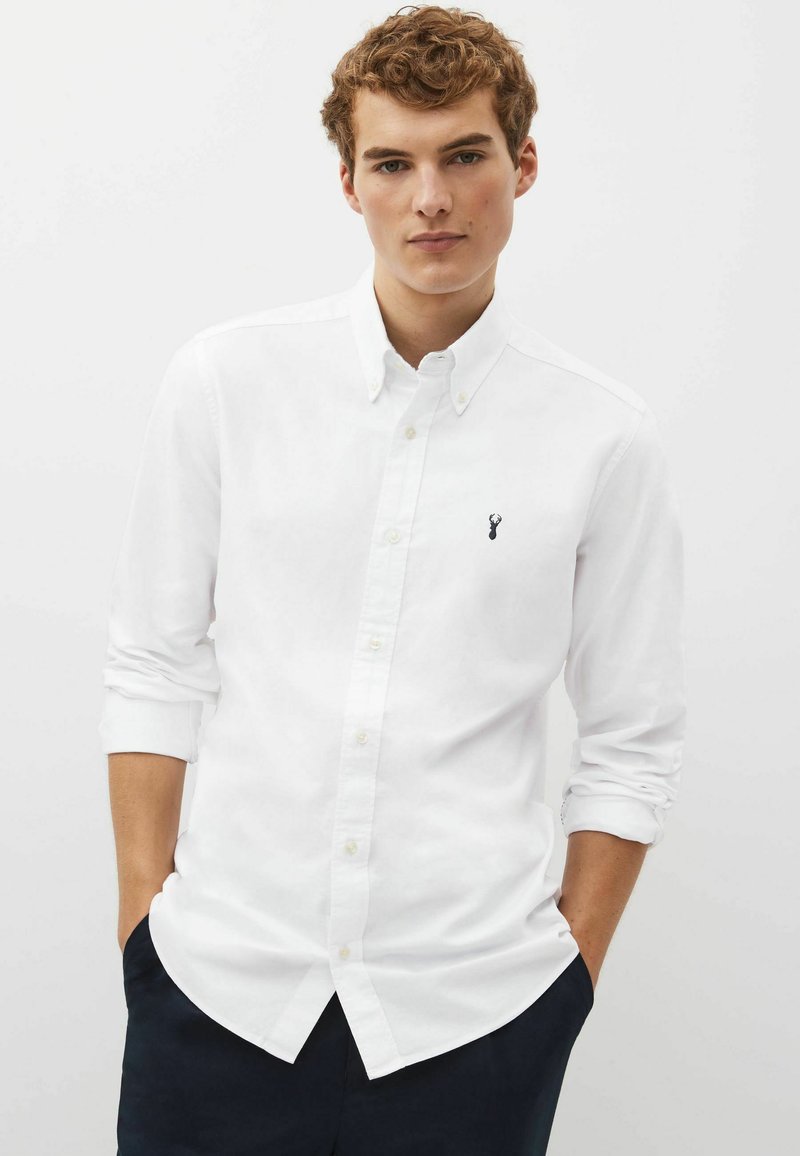 Camicia bianca con bottoni realizzata in cotone, con maniche lunghe, colletto e un piccolo logo nero ricamato sul petto.