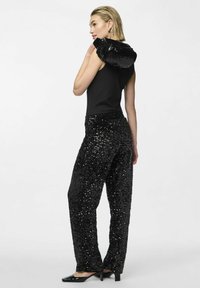 Haut sans manches noir avec une capuche en sequins brillants, associé à un pantalon noir à sequins amples. Texture lisse et détails scintillants tout au long.
