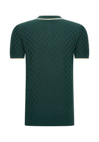 Polo de manga corta en punto verde oscuro con un patrón de tablero de ajedrez, cuello y puños acanalados con acentos en crema.