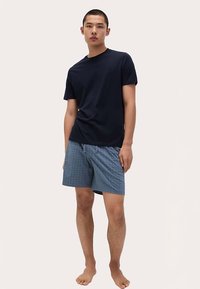 Camiseta de manga corta azul marino combinada con pantalones cortos azules con estampado. Los pantalones cortos presentan un diseño cuadriculado y una cintura elástica.