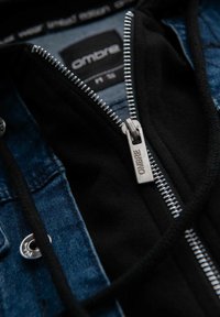 Giacca da uomo con cappuccio nero, tessuto in denim, zip argentata con dettagli "OMBRI" e fodera interna a contrasto.
