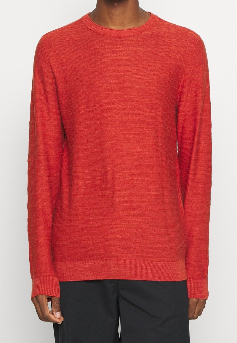 Pull rouge à manches longues en tissu texturé, avec un col rond et des poignets et un ourlet côtelés. Design simple et uni.