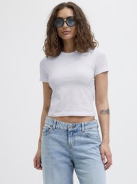 Hvit, kortermet, crop t-skjorte med tettsittende design og lys blå tekst. Kombinert med høyt liv, lys blå, slitte denimjeans.
