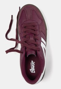 Baskets bordeaux avec une tige en cuir et en daim, des bandes latérales blanches, des lacets plats et une semelle en caoutchouc marron.