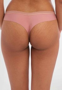 Stringondergoed van een zachte roze stof. Heeft een low-rise snit met een gladde textuur en twee horizontale strepen op de tailleband.