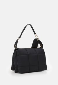 Czarna torebka pikowana, wykonana z materiału wypełnionego, z złotym zamkiem błyskawicznym i odpinanym paskiem na ramię. Charakteryzuje się strukturalnym, prostokątnym kształtem.