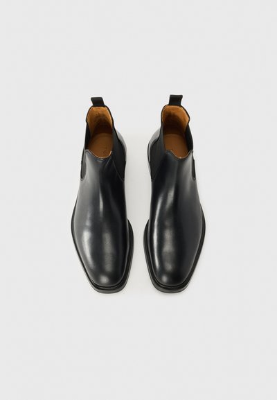 Svarta läder Chelsea-boots med en slät, glansig finish, spetsig tå, elastiska sidopaneler och dragflikar för enkel påtagning.