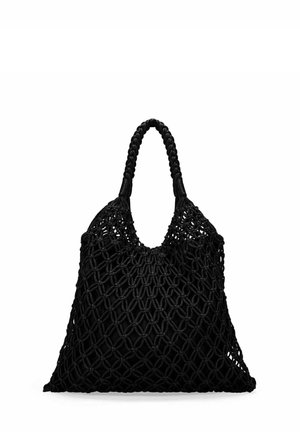 Bolsa tote negra de red tejida con un asa trenzada, vacía y de pie sobre un fondo blanco.