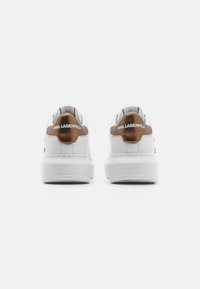 White sneakers with a textured brown heel accent, featuring a smooth leather upper, cushioned sole, and branded heel tab.