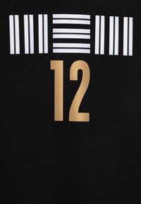 Černá látka zobrazuje velké zlaté číslo "12" a řadu bílých horizontálních pruhů nahoře. Textura vypadá mírně texturovaně.