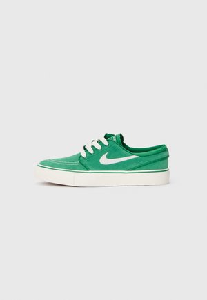 Grüne Leinenschuhe mit weißen Akzenten, runder Zehenform und Ösen für die Schnürsenkel. Verfügt über eine strukturierte Oberfläche und eine dicke weiße Sohle mit grünem Rand.